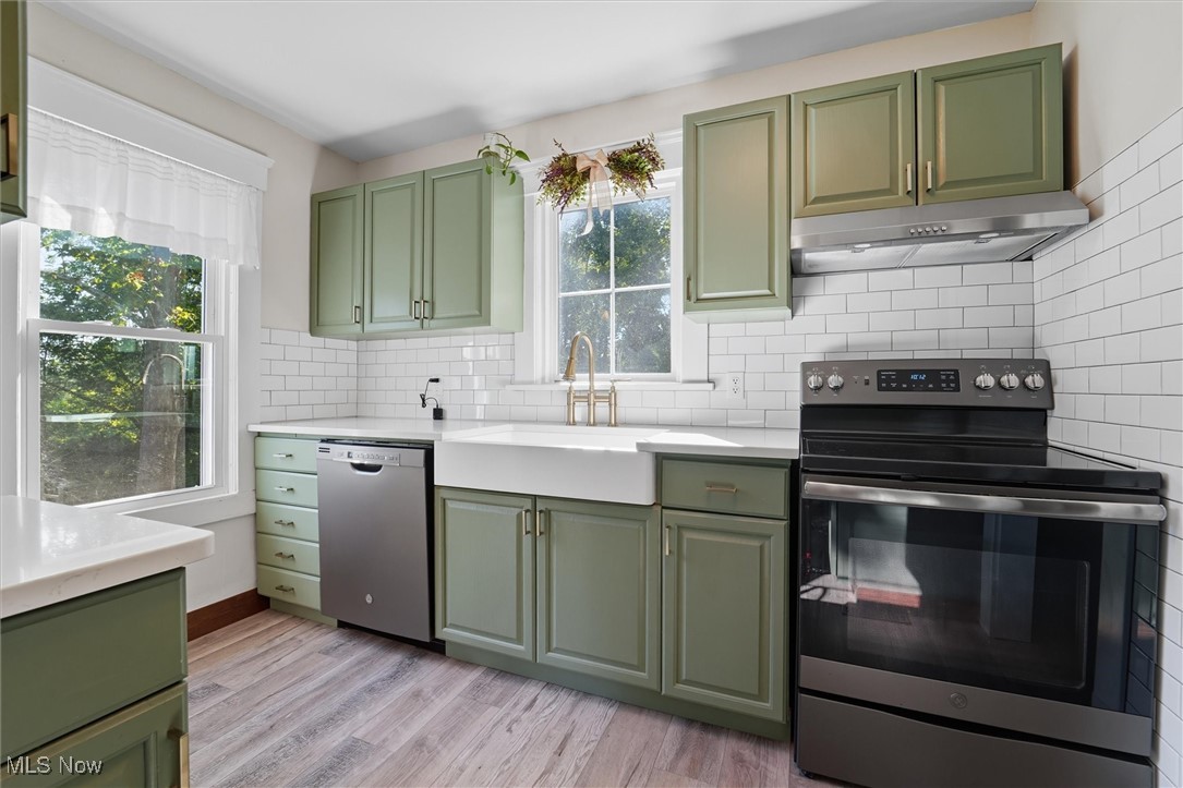 10536 Johnnycake Ridge Road Painesville, OH 44077 - Photo 8 of 40 Kitchen featuring green cabinetry, appliances with stainless steel finishes, plenty of natural light, and backsplash