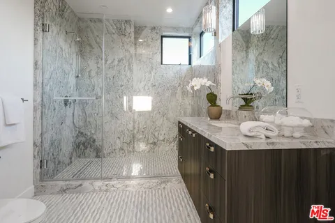 a bathroom with a granite countertop shower a sink and a mirror