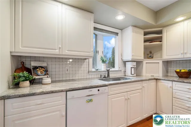 a kitchen with stainless steel appliances granite countertop a sink a window and cabinets