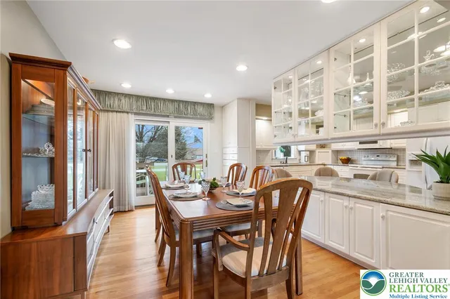 a dining room with stainless steel appliances granite countertop a dining table chairs and a refrigerator
