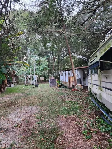 a view of a yard with a house and a forest