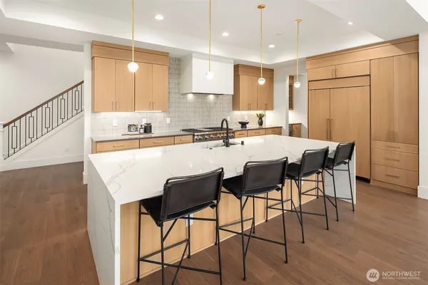 a kitchen with granite countertop a table chairs stove microwave and cabinets with wooden floor