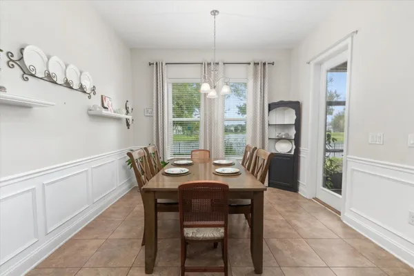 a dining room with furniture a kitchen and chandelier