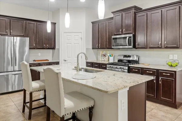 a kitchen with granite countertop stainless steel appliances a sink a stove top oven a refrigerator cabinets and a sink