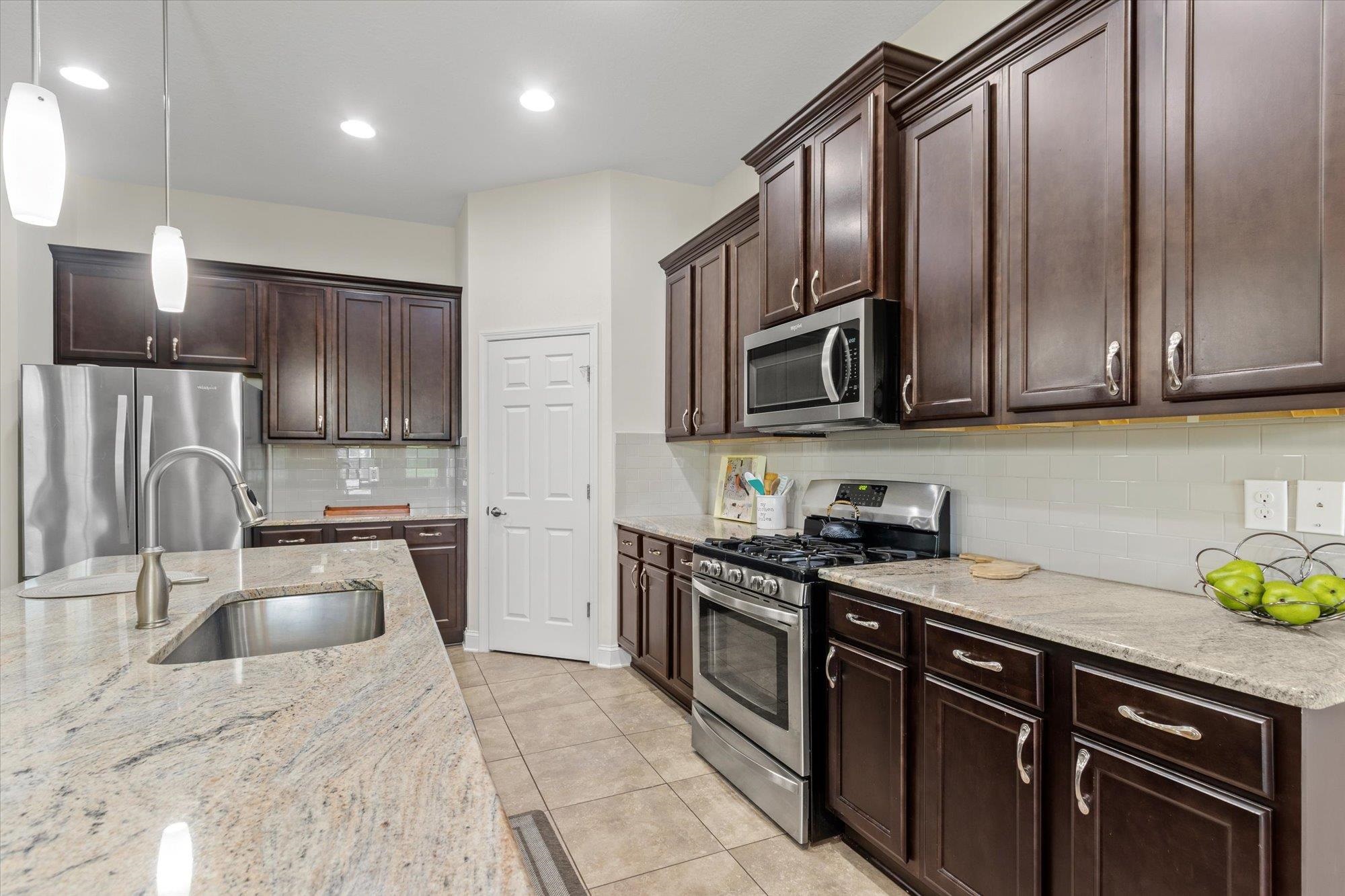 256 Vivian James Drive St. Augustine, FL 32092 - Photo 22 of 57 a kitchen with granite countertop stainless steel appliances a sink a stove top oven a refrigerator cabinets and a sink