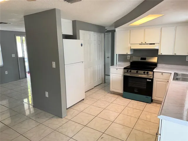 a kitchen with granite countertop a refrigerator and a stove top oven