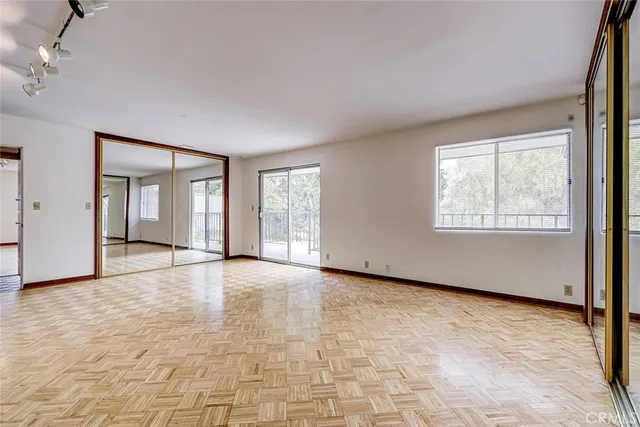 a view of an empty room with a window and kitchen view