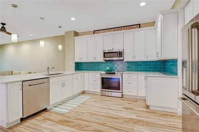 a large white kitchen with stainless steel appliances granite countertop a stove a sink and a refrigerator