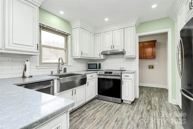 a kitchen with stainless steel appliances granite countertop a sink a stove a refrigerator and cabinets