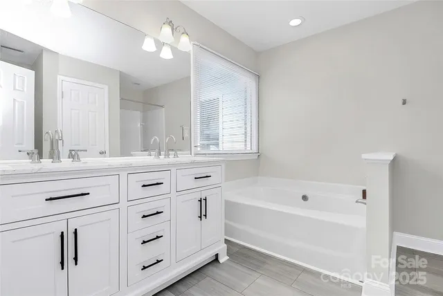 a bathroom with a bathtub sink double vanity and mirror