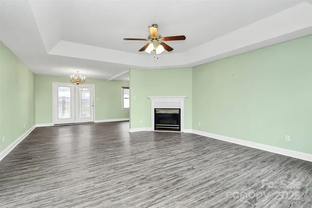 an empty room with wooden floor fireplace and windows