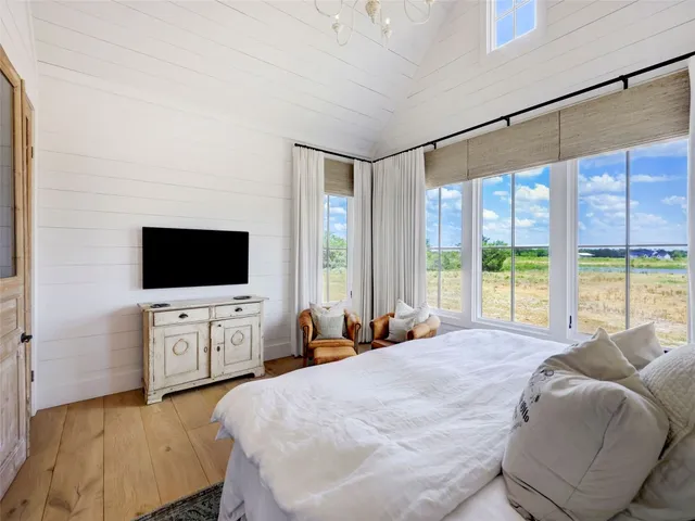 a large bedroom with a large bed and a flat tv screen on dresser