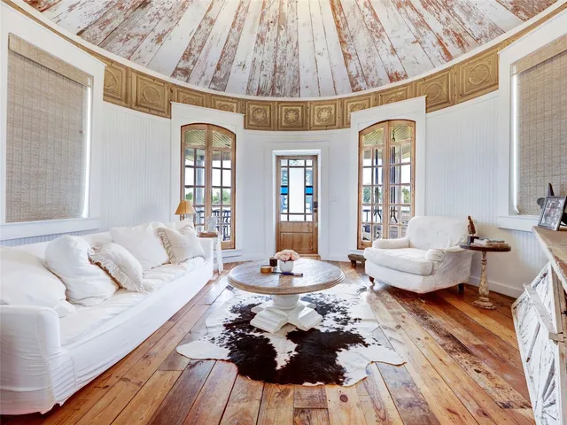 a bedroom with a bed and a large window with wooden floor