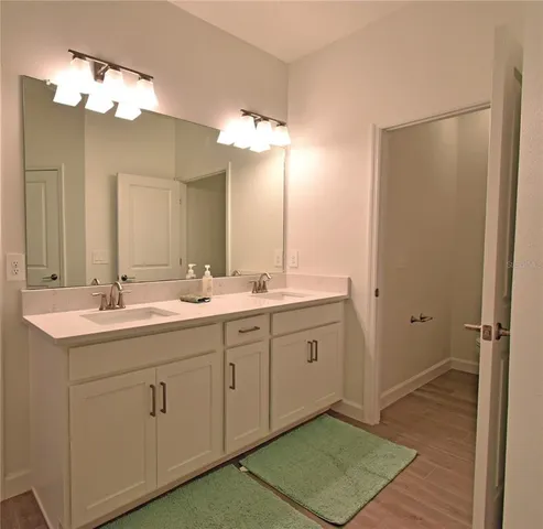 a spacious bathroom with a double vanity sink a mirror and a shower