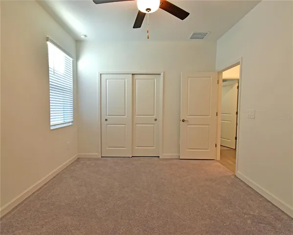 an empty room with windows and fan