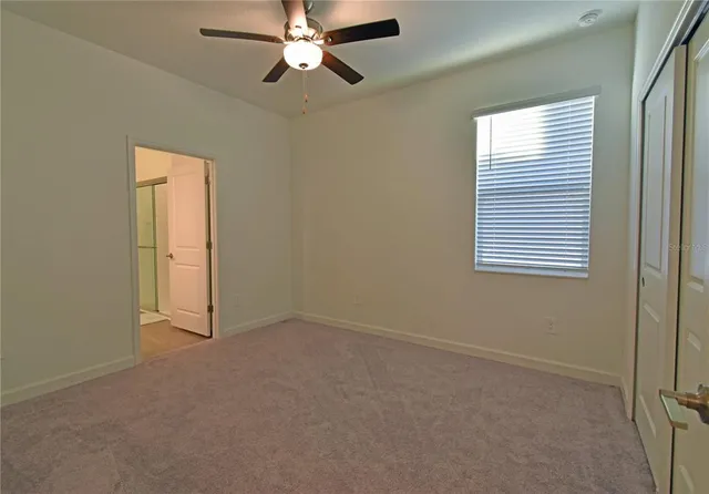 an empty room with windows and fan