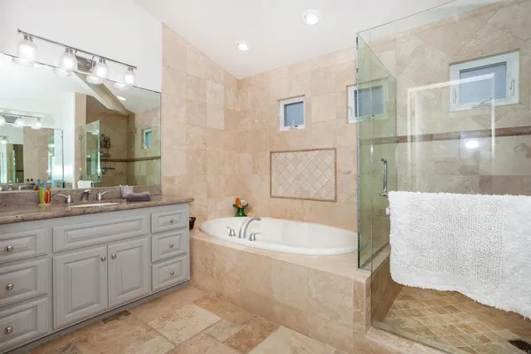 a spacious bathroom with a tub sink and mirror