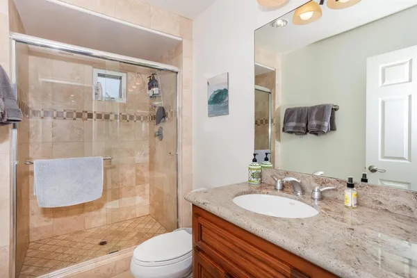 a bathroom with a granite countertop sink toilet mirror and shower
