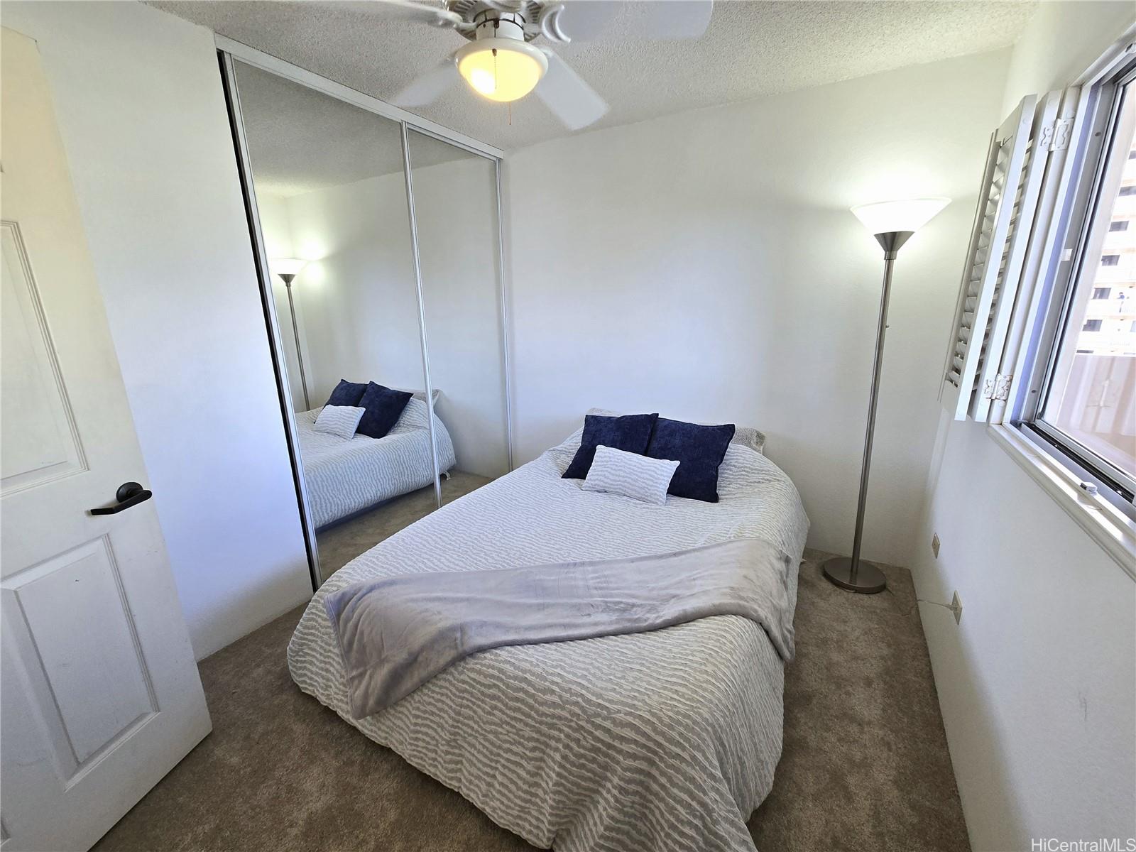 3075 Ala Poha Place, Unit 1504 Honolulu, HI 96818 - Photo 6 of 22 a bedroom with a bed and a lamp