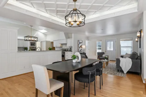 a kitchen with stainless steel appliances kitchen island granite countertop a stove a sink dishwasher a refrigerator and white cabinets with wooden floor