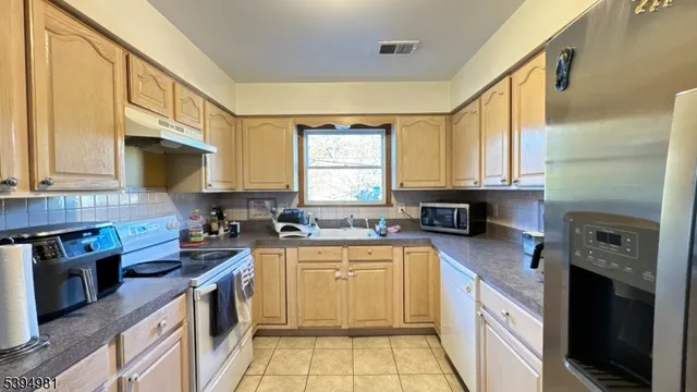a kitchen with a sink a stove top oven cabinets and a window