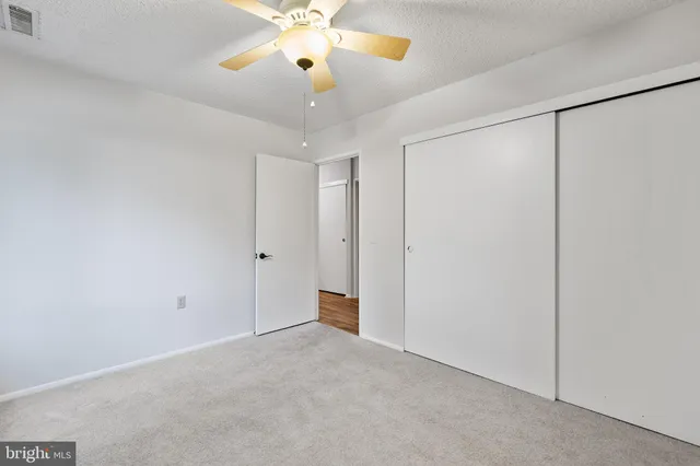 an empty room with closet and a chandelier fan
