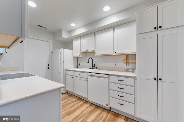 a kitchen with white cabinets and sink