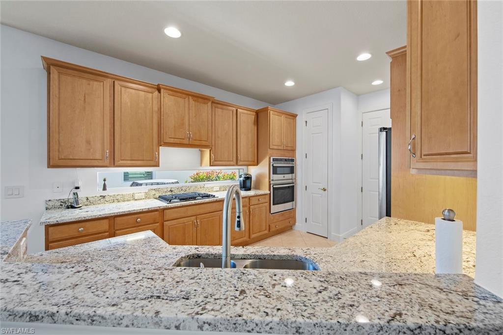 19924 Maddelena Circle Estero, FL 33967 - Photo 17 of 35 a large kitchen with kitchen island granite countertop wooden cabinets a granite counter tops and a window