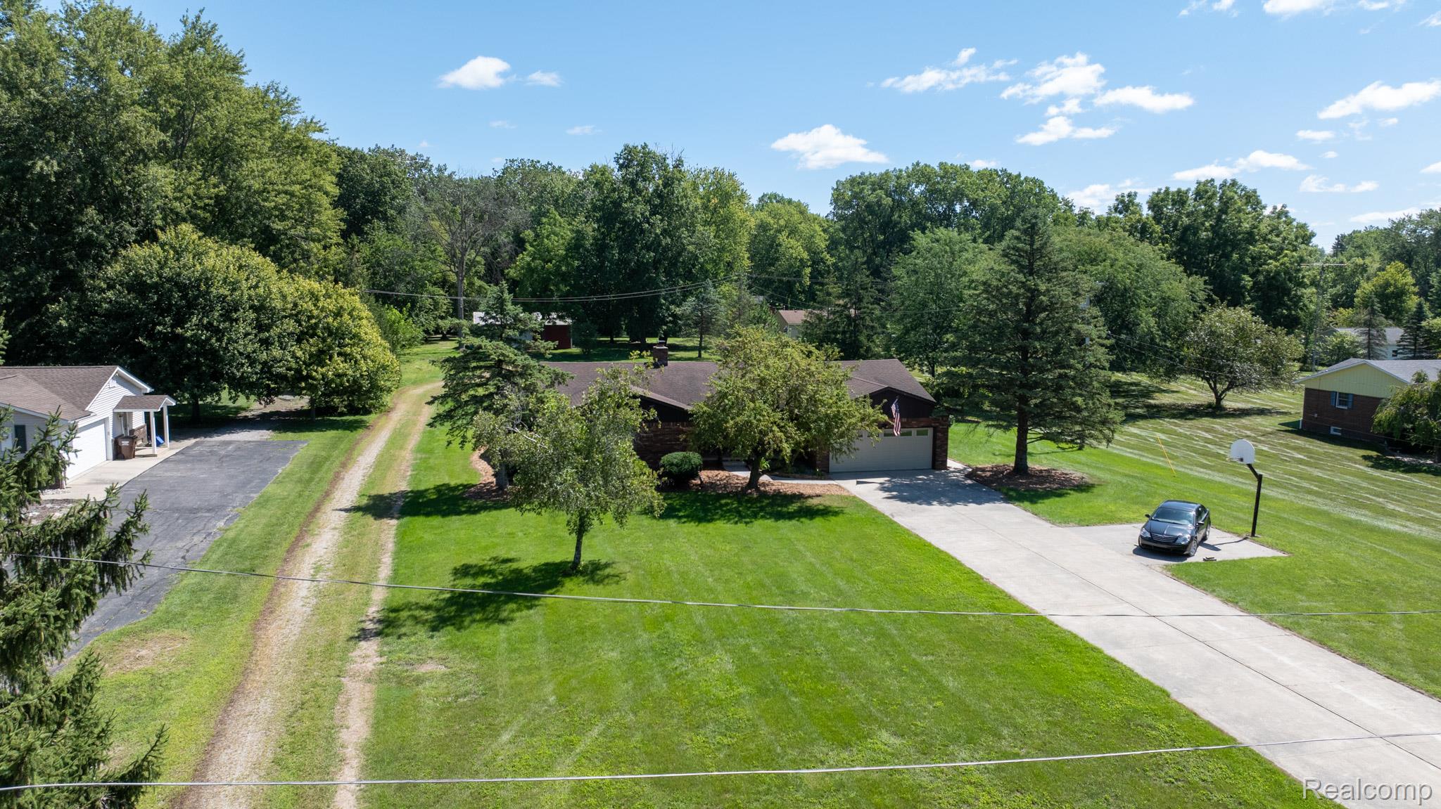 12900 Maxwell Road Carleton, MI 48117 - Photo 8 of 59 Expansive lot with lush green lawn, mature trees, and a paved driveway