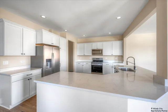 a kitchen with stainless steel appliances granite countertop a refrigerator sink and white cabinets