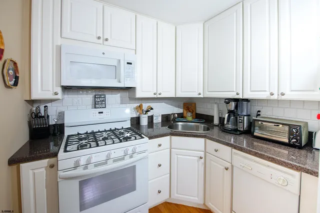 a kitchen with granite countertop white cabinets and white appliances