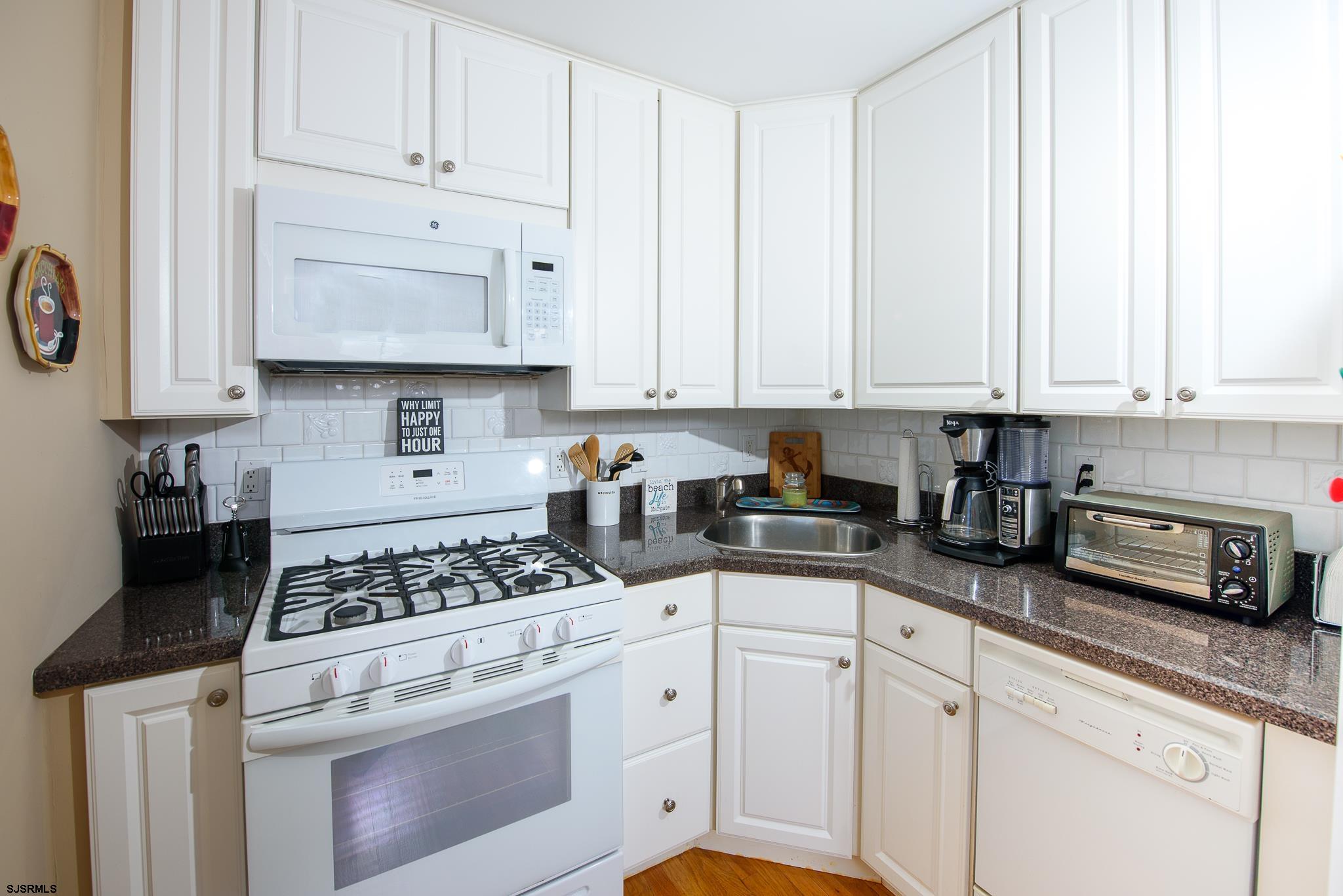 7 South Franklin Avenue, Unit 7 Margate City, NJ 08402 - Photo 5 of 16 a kitchen with granite countertop white cabinets and white appliances