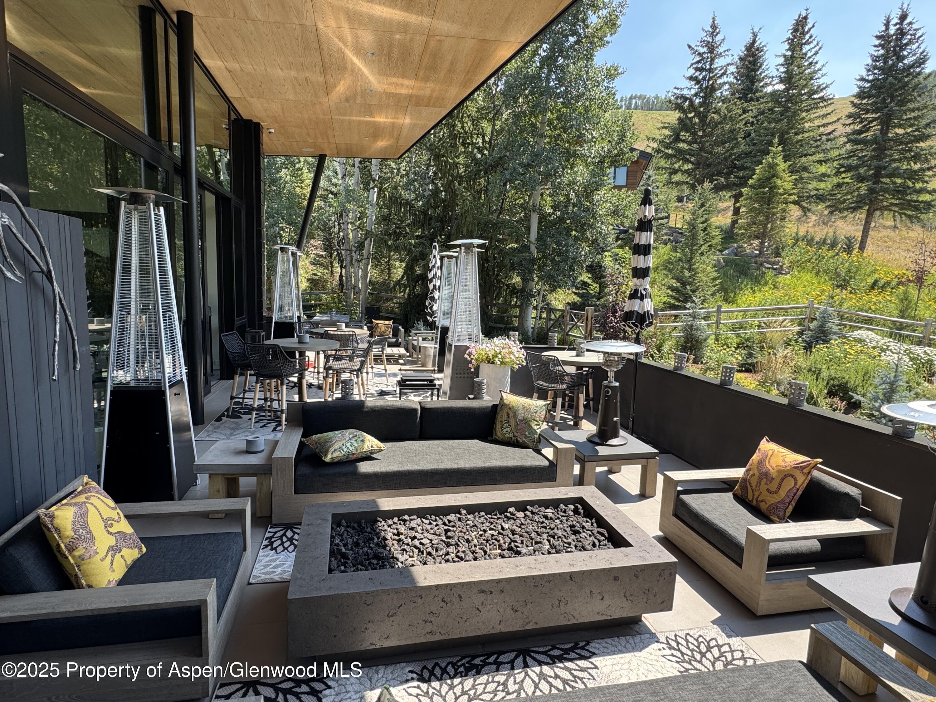 296 Glen Dee Road Aspen, CO 81611 - Photo 19 of 25 a view of a patio with couches chairs potted plants and a large tree