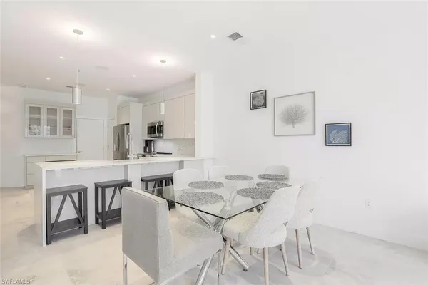 a kitchen with a dining table chairs and white cabinets