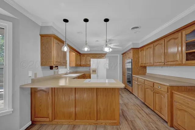a view of a kitchen with kitchen island granite countertop wooden floor cabinets and a chandelier