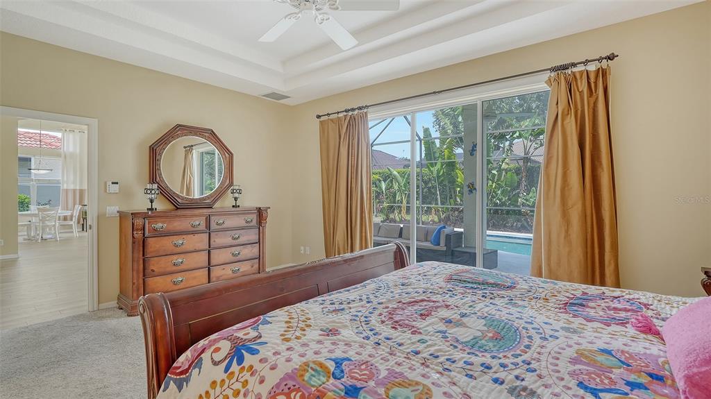 7717 US Open Loop Lakewood Ranch, FL 34202 - Photo 20 of 95 a bedroom with a bed a mirror on dresser and a large window