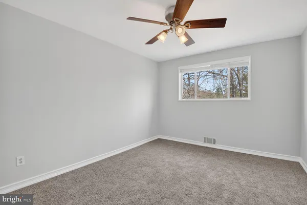 an empty room with a window and a fan