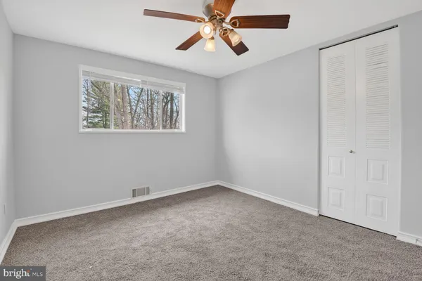 an empty room with windows and fan