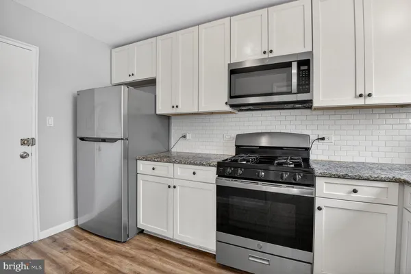 a kitchen with cabinets stainless steel appliances and wooden floor
