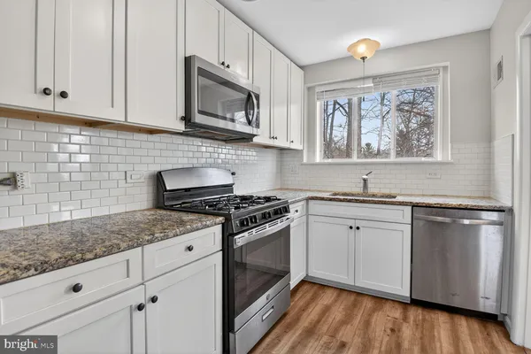a kitchen with stainless steel appliances granite countertop a stove a sink and white cabinets