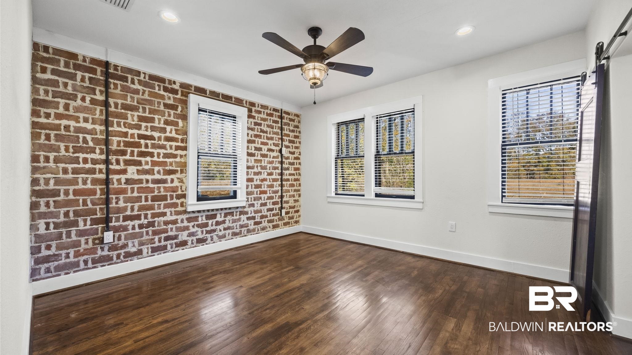 24701 Highway 98 Elberta, AL 36530 - Photo 12 of 32 Spare room with brick wall, dark wood-type flooring, a barn door, recessed lighting, and a ceiling fan