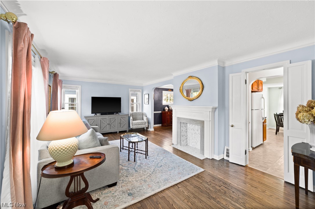 15722 Munn Road Cleveland, OH 44111 - Photo 2 of 32 Living room with refinished hardwood floors, crown molding and a fireplace