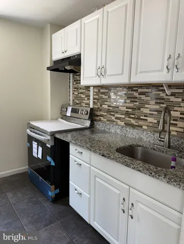 a kitchen with granite countertop a sink a stove and cabinets