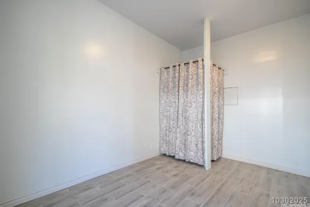an empty room with wooden floor and windows with exposed radiator
