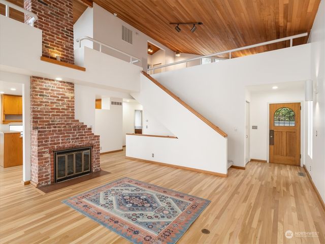 a view of an empty room with wooden floor fireplace and a window