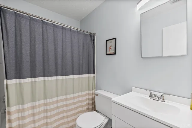 a bathroom with a sink a toilet and shower curtain