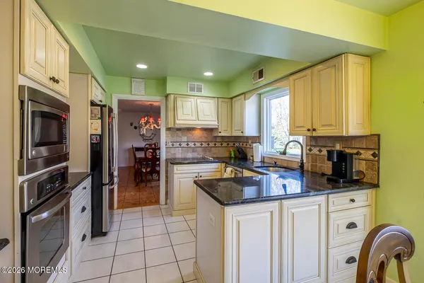 a kitchen with stainless steel appliances granite countertop a stove refrigerator and a sink