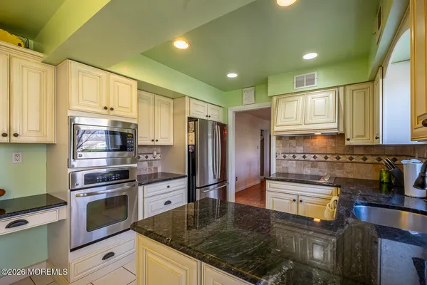 a kitchen with stainless steel appliances granite countertop a stove a sink and a refrigerator