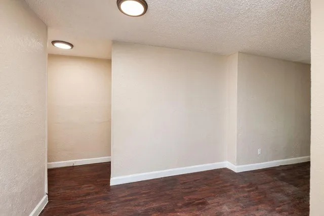 an empty room with wooden floor ceiling fan and windows