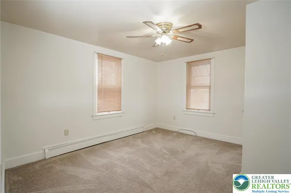 an empty room with windows and fan